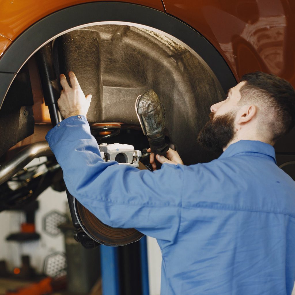 KFZ Gutachter Zentrale | mechanic with tool wheel hands mechanic blue work clothes KFZ Gutachter Zentrale